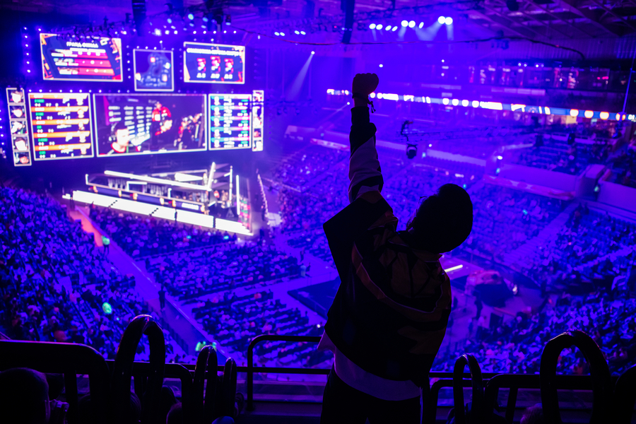Big esports event. Video games fan on a tribune at tournament`s arena with hands raised. Cheering for his favorite team. Photo 160802909 © Roman Kosolapov | Dreamstime.com